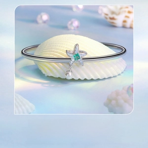 Detailed close-up of a silver starfish charm bracelet with green gemstone and white pearl
