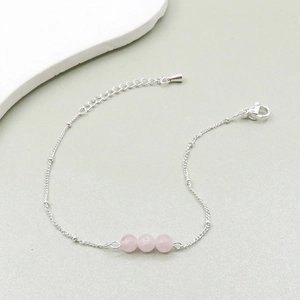 Detail of silver chain bracelet featuring three pink crystal beads and lobster clasp