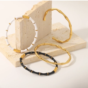 Detailed close-up of C-shaped bamboo joint bangles in gold and enamel on a stone base
