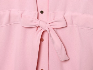 Gros plan sur le tissu d'une chemise rose avec nœud papillon et boutons dorés détaillés