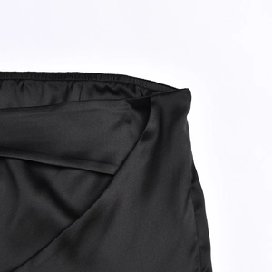 Détail du tissu en satin noir brillant et des coutures fines sur une robe moulante