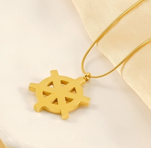 Detailed close-up of 18K gold rudder pendant with snake chain on elegant stone surface