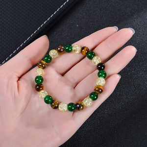 Detail of beaded tiger eye and citrine bracelet held by hand against black leather