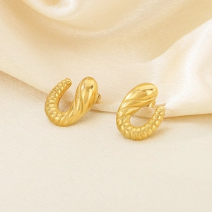 Macro shot of 18k gold stainless steel croissant hoop earrings on cream silk fabric