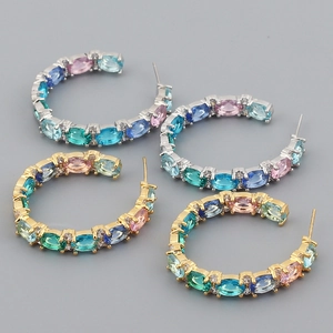 Detail of gold and silver C-shaped earrings inlaid with colorful oval zircon stones