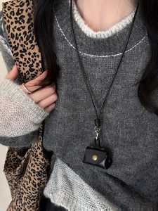 Close-up of black leather mini pouch necklace with gold snap on a grey knit sweater