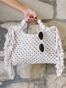 Detail of macrame woven crossbody bag with wooden bead handle and long tassels