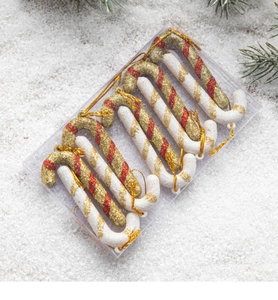 Close-up of 6-piece Christmas candy cane ornaments with red gold glitter on snow texture