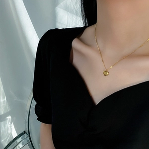 Detail view of a polished gold heart pendant necklace worn on a female model's neck