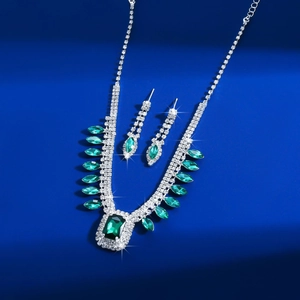 Detailed macro view of silver necklace and earrings set with emerald square crystals