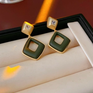 Macro view of gold rhombic earrings with green inlay and crystals in a velvet box