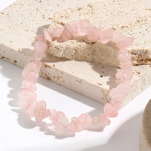 Close-up of irregular natural pink quartz stone beads on a textured stone surface