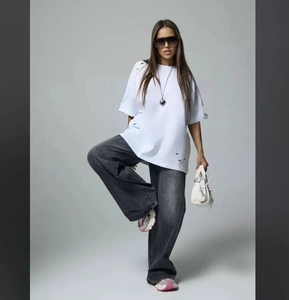 Full view of white distressed oversized tee and dark grey wide-leg washed jeans