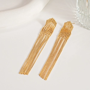 Macro shot of long gold metallic tassel earrings with geometric arrow-shaped top detail
