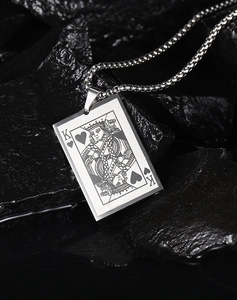 Detailed view of silver poker King of Hearts pendant with snake chain on dark stones