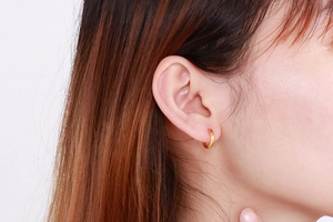 Detail view of a minimalist 304 stainless steel gold hoop earring worn by a model