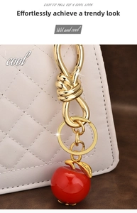 Detail of red cherry resin pendant with gold hollow hardware on a white quilted bag