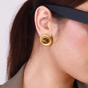 Close-up of golden vintage round stud earring with tiger eye stone on model's ear