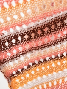 Nahaufnahme von bunt gestreiftem Strickstoff mit feinen Häkel-Hohlraum-Details