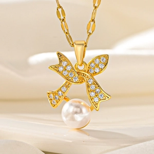 Elegant gold bow necklace with sparkling crystals and a white pearl drop on silk