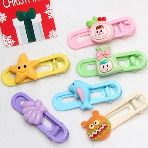 Close-up of six colorful U-shaped cartoon hair clips on white textured fabric background