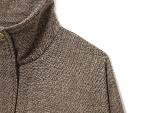 Detail of herringbone wool bomber jacket featuring textured weave and metal snap buttons