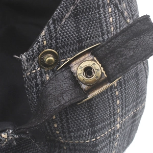 Detail of plaid newsboy cap featuring leather strap and vintage bronze metal buttons