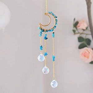 Macro view of blue crystal moon suncatcher with golden chains and faceted glass prisms