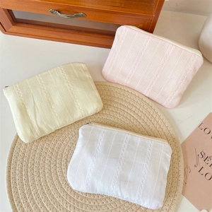 Three quilted fabric cosmetic bags with lace texture on a round woven placemat