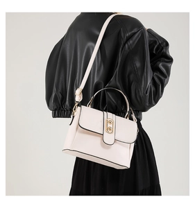 Detailed view of cream PU leather shoulder bag with gold hardware on a model