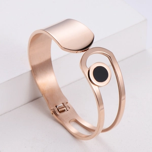 Minimalist rose gold geometric open bangle with a round black inlay on a stone base