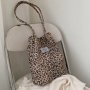 Close-up of leopard print canvas tote bag with black woven label detail on white chair