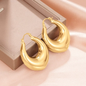 Macro view of chunky golden teardrop earrings with high-polish finish on silk