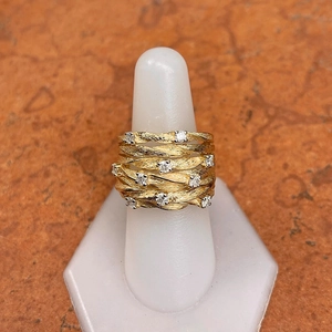 Close-up of a wide gold vine wrap ring featuring sparkling round zirconia on textured bands