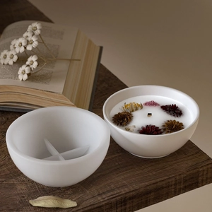 Artistic detail of round silicone mold and wax candle bowl with dried flower accents