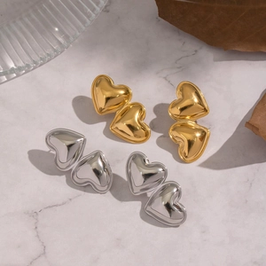 Macro shot of polished gold and silver heart studs on a marble surface backdrop