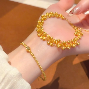 Detail of 24K gold plated layered bead bracelet and thin chain on model wrist