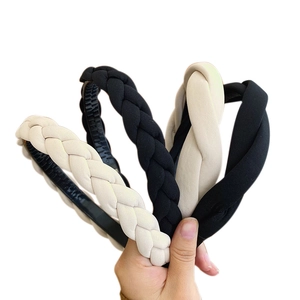 Hand holding braided twist sponge headbands in black and beige colors with soft fabric