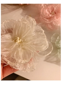 Close-up of a handmade white mesh flower hair clip with layered soft fabric petals