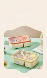 Close-up of dual-compartment bento box with matching spoon and smiley air vent