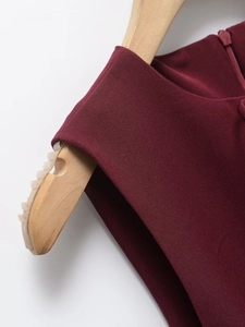 Detail of burgundy dress fabric texture and invisible zipper on a wooden hanger