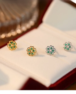Macro shot of S925 silver flower earrings with green gemstones in a white velvet box
