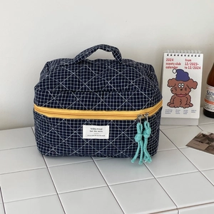 Close-up of quilted navy blue checkered makeup bag with yellow zipper and cord pulls