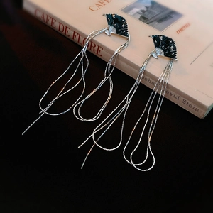 Detail of fan-shaped drop earrings with silver tassels on a vintage book backdrop