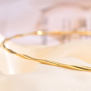 Macro shot of gold twisted neck chain detail over elegant cream silk background