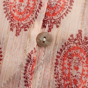 Macro shot of shell buttons and metallic gold thread weave on beige printed shirt
