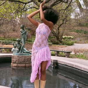 Détail de robe sans manches en dentelle rose avec motifs floraux et ourlet asymétrique