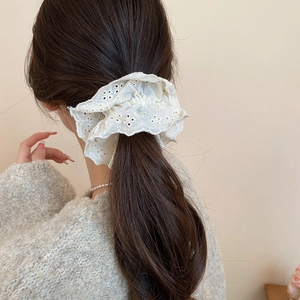 Detail of white oversized lace scrunchie with eyelet embroidery on wavy flower edges