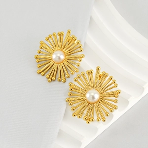 Detail of vintage gold sunburst earrings with a central pearl on a wavy pedestal