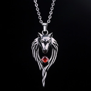 Macro shot of silver wolf head necklace with a square red gemstone on black background